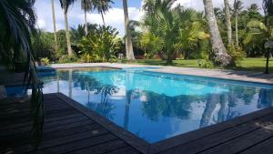 a swimming pool with blue water and palm trees at Villa ManaOra in Taravao