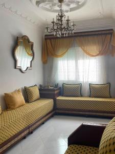 a living room with two beds and a chandelier at Casa Amina in Martil