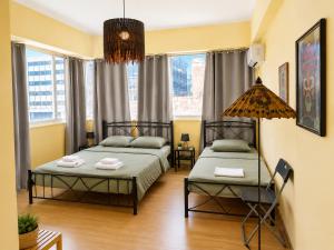 two beds in a room with two windows at Acropolis Center Rooms in Athens