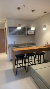 a kitchen with a large wooden table with four bar stools at GAV Beach Resort - Smart in Salinópolis