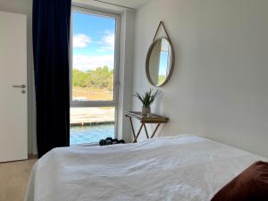 a bedroom with a bed and a mirror and a window at Bryggebyen in Arendal