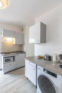 a kitchen with white cabinets and a washing machine at Studio équipé,Terrasse,Marina & plage à pied in Saint-François +13 photos
