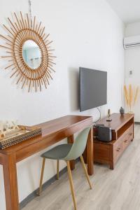 a desk with a monitor and a chair and a mirror at Studio équipé,Terrasse,Marina & plage à pied in Saint-François