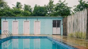 a blue building with pink doors next to a swimming pool at Jambhul Nest studio Pool & Rainforest Escape in Dhamni