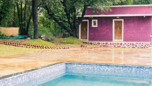 a pink house with a swimming pool in front of a house at Jambhul Nest studio Pool & Rainforest Escape in Dhamni +3 photos