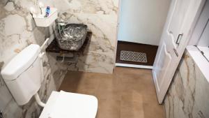a bathroom with a white toilet and a sink at Jambhul Nest studio Pool & Rainforest Escape in Dhamni
