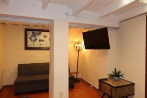 a living room with a couch and a tv on a wall at Escondite de Galarza 26 in Guanajuato