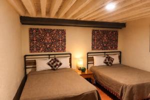 a bedroom with two beds and a wooden ceiling at Escondite de Galarza 26 in Guanajuato