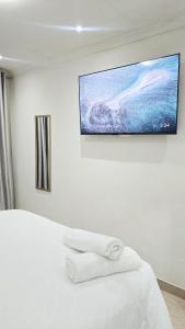 a bedroom with a white bed with towels on it at HMT Guest House in Thohoyandou