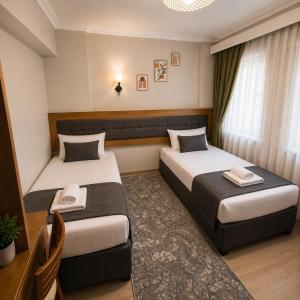 a hotel room with two beds and a desk at Kestanbol Hotel in Çanakkale