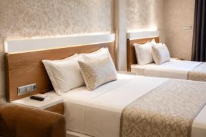 a hotel room with two beds and a chair at Hôtel Aguelmam in Khenifra