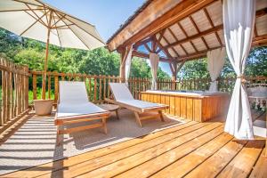 a wooden deck with two chairs and an umbrella at Cabane La Douce Parenthèse - Spa & Sauna in Brive-la-Gaillarde