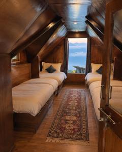 a room with three beds with a window and a rug at Prathmesh Homestay in Bijanbāri Bāzār