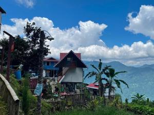 a house on a hill with mountains in the background at Prathmesh Homestay in Bijanbāri Bāzār