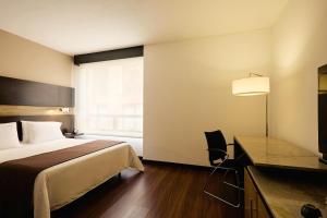 a hotel room with a bed and a desk and a window at Mercure Bogota BH Retiro in Bogotá