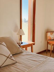 a bedroom with a bed with a table and a window at Hostería Rural Les Aldudes in San Andrés de Giles +26 photos