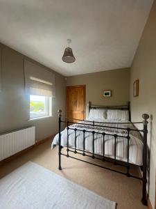 ein Schlafzimmer mit einem Bett mit weißer Bettwäsche und einem Fenster in der Unterkunft Three Sisters in Dingle
