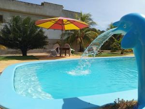 a dolphin fountain in a pool with an umbrella at Pousada Nativ0s in Baía Formosa