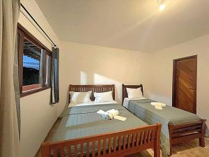 two twin beds in a room with a window at Pousada Nativ0s in Baía Formosa