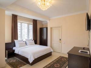 a bedroom with a white bed and a chandelier at Taugul Hotel in Almaty