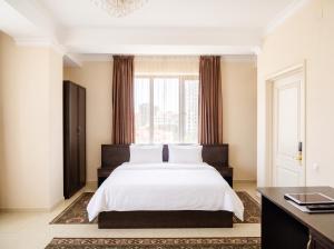 a bedroom with a white bed and a window at Taugul Hotel in Almaty