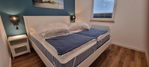 an unmade bed in a bedroom with a blue wall at Ferienhaus Wellenklang in Glowe