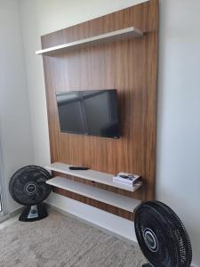 a flat screen tv on a wall with two chairs at Brisa do mar região dos lagos in São Pedro da Aldeia