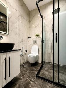 a bathroom with a toilet and a glass shower at Sea Breeze Apartments in Baku +8 photos