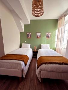 two beds in a room with green walls at L'écrin d'Hélène in Lormes