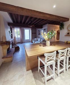 a kitchen with a large wooden table and white chairs at L'écrin d'Hélène in Lormes