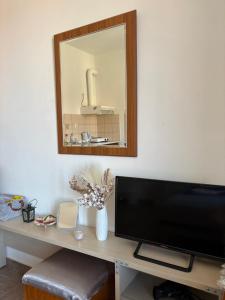 a living room with a television and a mirror at Vista del Mare Rooms 2 in Agios Ioannis Kaspaka