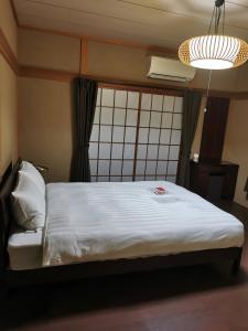 a bedroom with a bed with a white sheets and a light at Villa9 in Onjuku