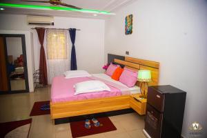 a bedroom with a bed with pink sheets and colorful pillows at Hôtel Akwin Kpalimé in Palimé