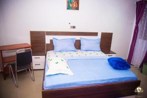 a bedroom with a bed with blue sheets and a desk at Hôtel Akwin Kpalimé in Palimé