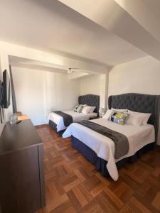 a bedroom with two beds and a flat screen tv at La Posada de Don Manuel in Santiago Sacatepéquez +64 photos