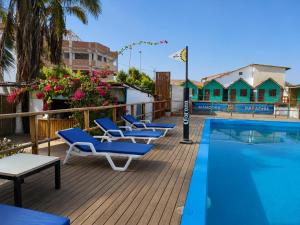a row of lounge chairs next to a swimming pool at Wild Rover Beach Mancora in Máncora