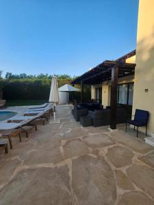 a patio with a bunch of chairs and an umbrella at Private Villa Heated Pool & Enclosed Garden in Hurghada