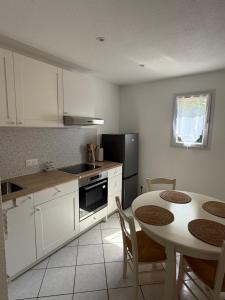 a kitchen with white cabinets and a table with chairs at Pavillon Le Luc in Ozillac +3 photos
