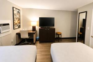 a hotel room with a bed and a desk and a tv at Rocky Mount Motel near Hwy 220 in Rocky Mount