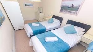 a bedroom with two beds with blue and white sheets at Cloudbreak Hot Tub Log Burner Dogs Welcome in Braunton