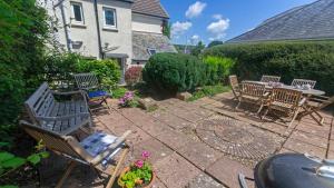a patio with chairs and a table and a table and chairs at Cloudbreak Hot Tub Log Burner Dogs Welcome in Braunton