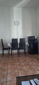 two chairs and a table with a clock on the wall at SIM residence in Maniago