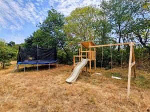 a playground with a slide and a swing set at Les Petits Champs Islandais in Manas-Bastanous