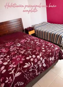 a bedroom with two beds with a red floral bedspread at Un pequeño paraíso en Malinalco in Malinalco