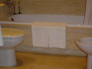 a bathroom with a toilet and a bath tub with towels at Apartamentos Esperanza del Mar in Portonovo