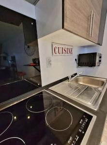 a kitchen with a sink and a stove at La Ch'tite Maison in Masnières