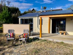 two chairs sitting on a porch next to a building at The Shed in Manapouri