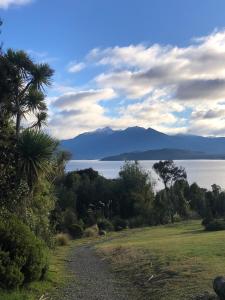 a gravel road with a view of the water and mountains at The Shed in Manapouri +1 photo