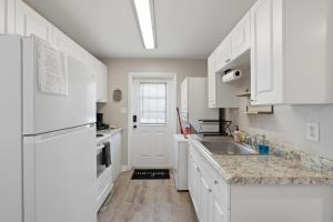 a white kitchen with a sink and a refrigerator at Amazing 2BR Queen 8mins SODO & 4mins ORMC in Orlando