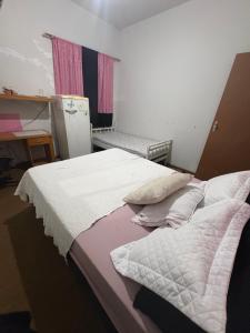 a bedroom with two beds and a refrigerator at POUSADA OCZ Centro1 in Osvaldo Cruz